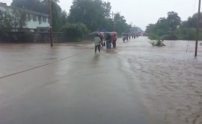 मुंबई से सटे पालघर में भारी बारिश के बाद लोगों को रस्सी के सहारे पार करनी पड़ी सड़क