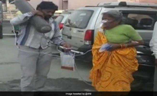 लापरवाही: बुजुर्ग मां का ऑक्सीजन सिलेंडर कंधे पर लाद अस्पताल में एंबुलेंस का इंतजार करता रहा बेटा