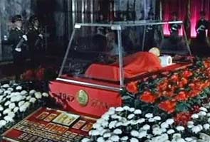 Kim Jong-Il body displayed behind glass, flowers