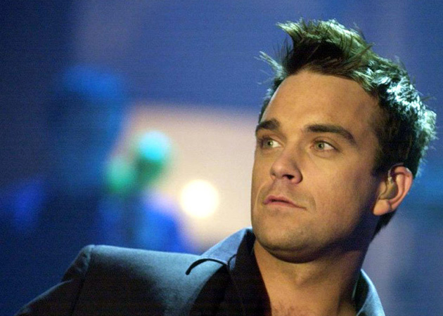 Robbie Williams performs with naked models