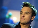 Robbie Williams performs with naked models